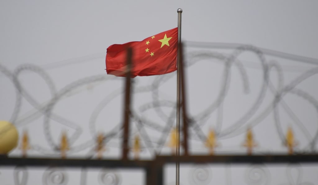 The Chinese flag flies behind razor wire at a housing compound in Yengisar, south of Kashgar in Xinjiang. Pervasive security has subdued ethnic unrest in the region. Photo: AFP