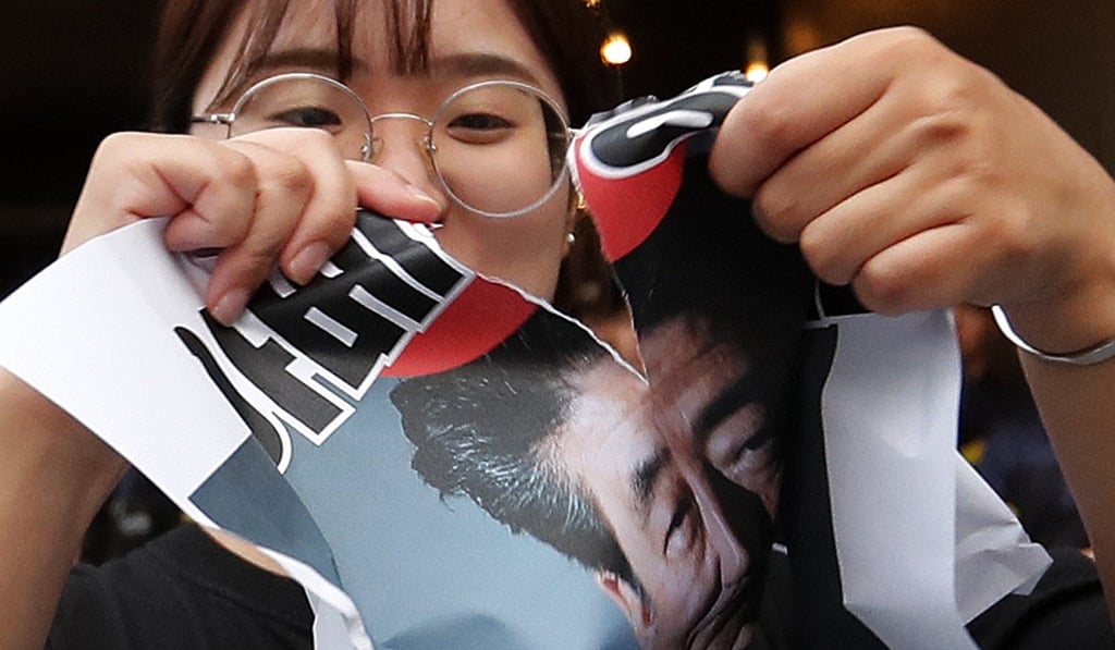 A South Korean protester tears up a picture of Japanese Prime Minister Shinzo Abe during a rally in Seoul. Photo: AP