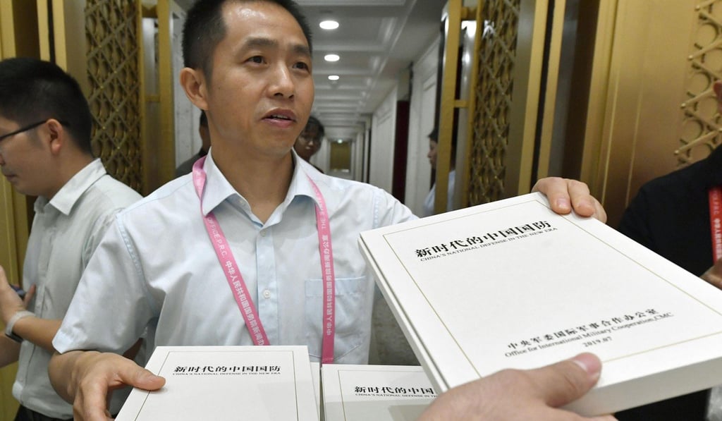 An official hands out copies of China’s latest defence white paper to journalists in Beijing on Wednesday. Photo: Kyodo