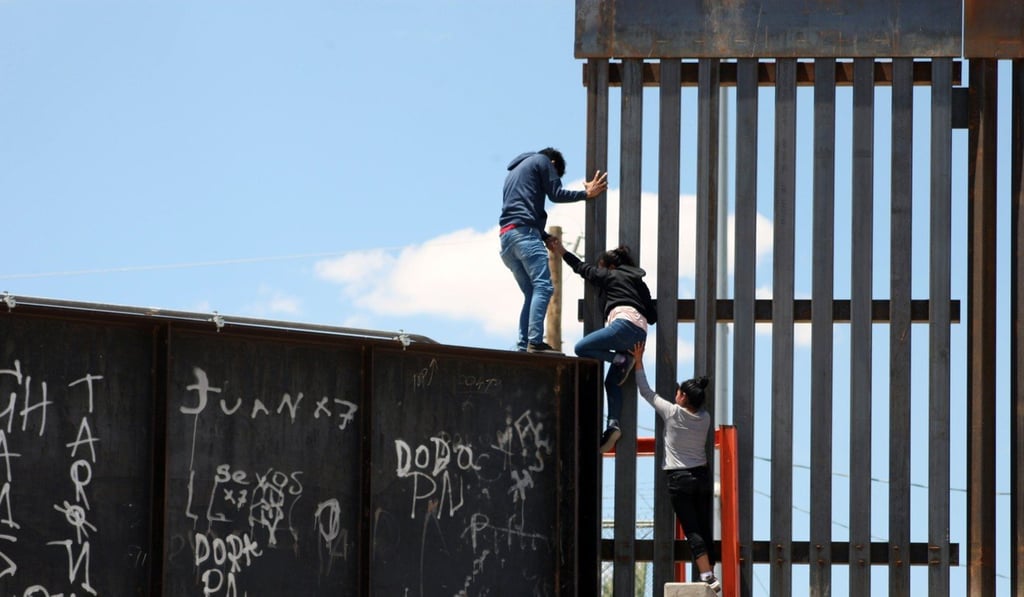 A group of people try to scale a section of the border wall to enter the US from Mexico on July 8. Photo: EPA