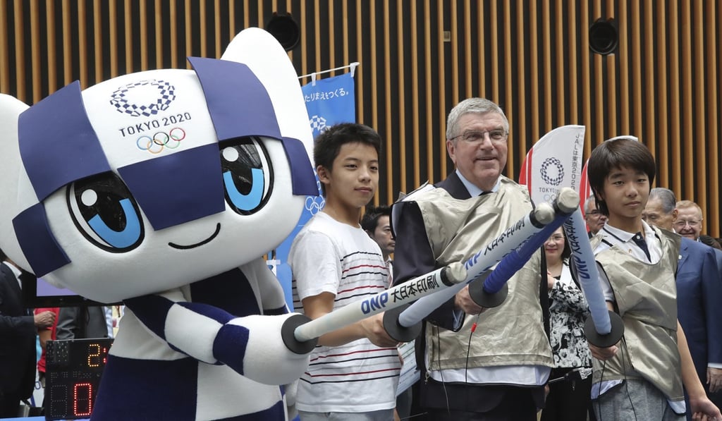 Thomas Bach poses with the Tokyo Olympics mascot and two Japanese secondary school students in Tokyo during the countdown to the Games. Photo: Xinhua