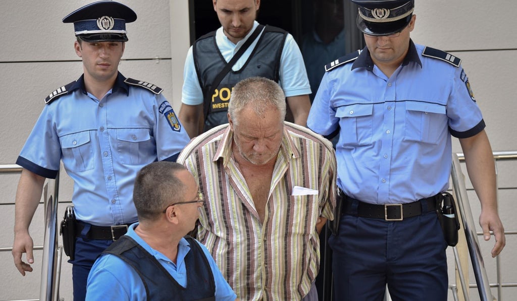 Police officers escort Gheorghe Dinca, the suspect in the case of rape and murder of two teenage girls. Photo: AP Police officers escort Gheorghe Dinca, the suspect in the case of rape and murder of two teenage girls. Photo: AP