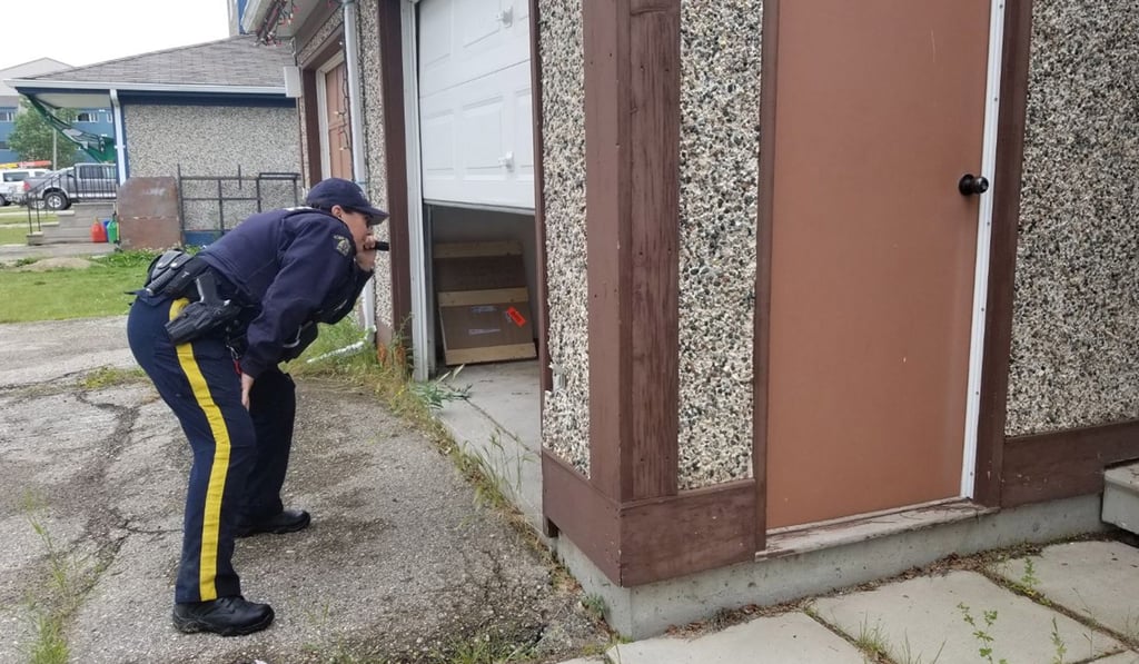 An RCMP officer searches a garage in the Gillam area of Manitoba, Canada, on Sunday. Photo: RCMP via EPA-EFE