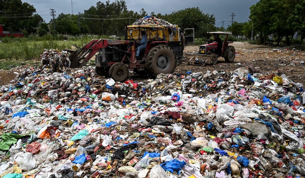 Municipal workers load garbage into a dump truck at a trash site full of plastic bags in Islamabad. Photo: AFP