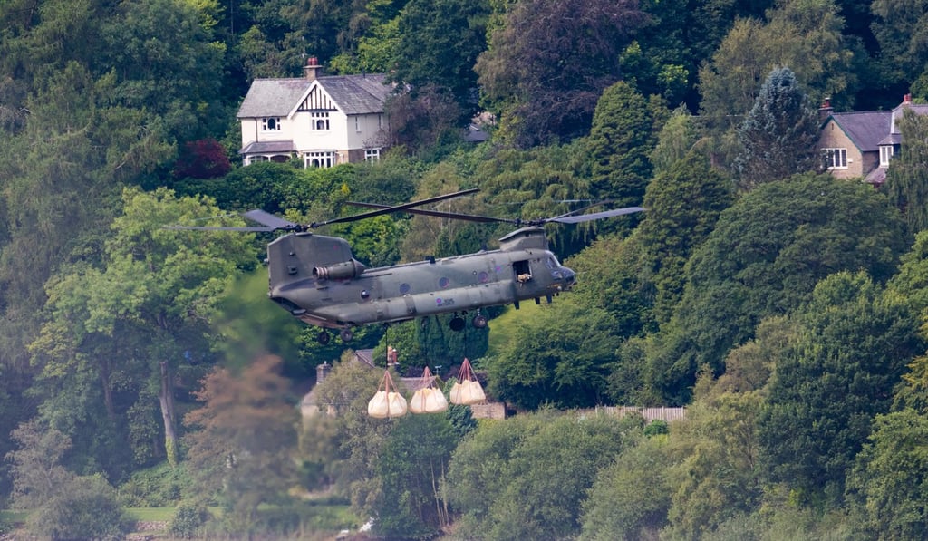 A British Royal Air Force (RAF) Chinook helicopter prepares to drop sand bags on the damaged dam. Photo: EPA A British Royal Air Force (RAF) Chinook helicopter prepares to drop sand bags on the damaged dam. Photo: EPA