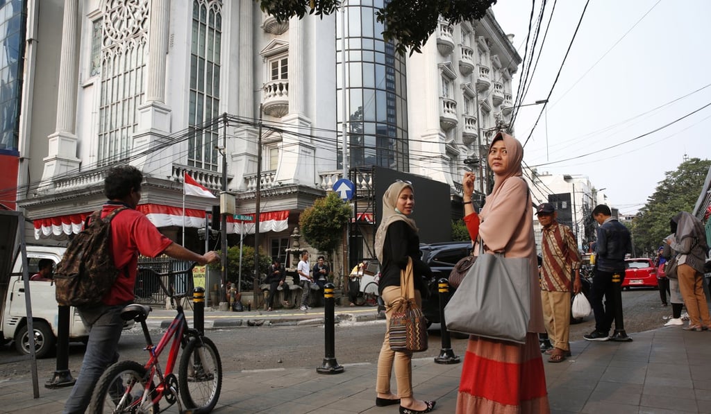 Passengers wait outside an MRT station in Jakarta on Sunday. Photo: EPA