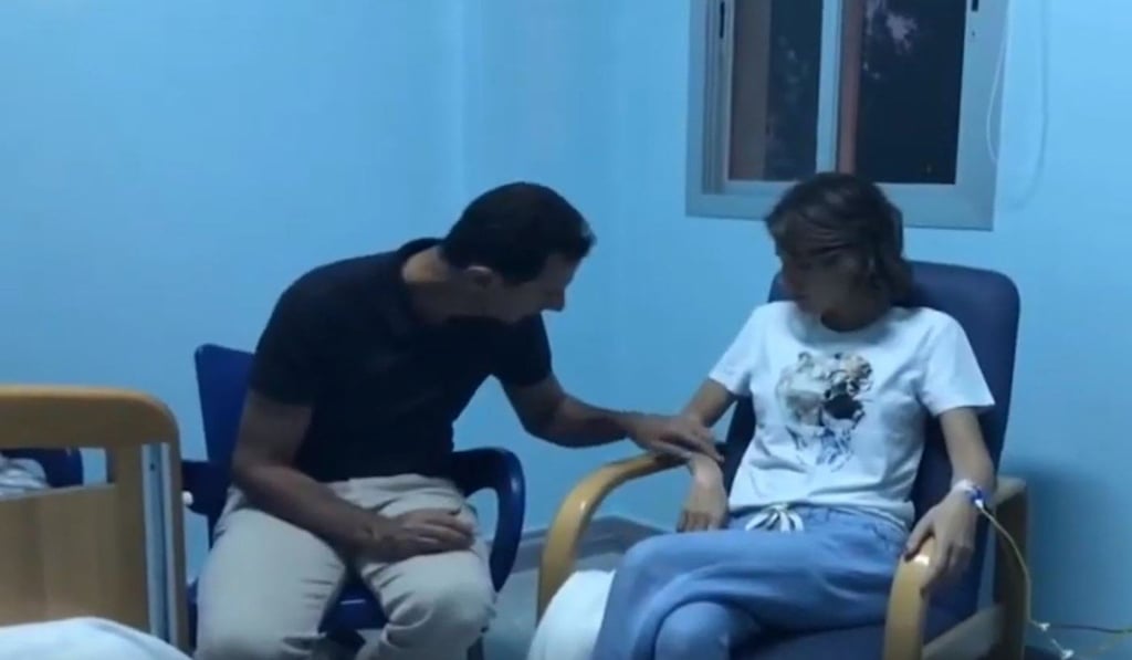 Asma al-Assad hooked up to a drip, smiling and sitting next to her husband, in a hospital room. File photo: Handout