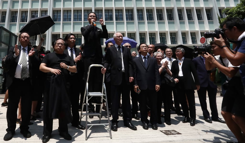 Lawmaker Dennis Kwok stands on a ladder as he speaks outside the Department of Justice. Photo: Jonathan Wong