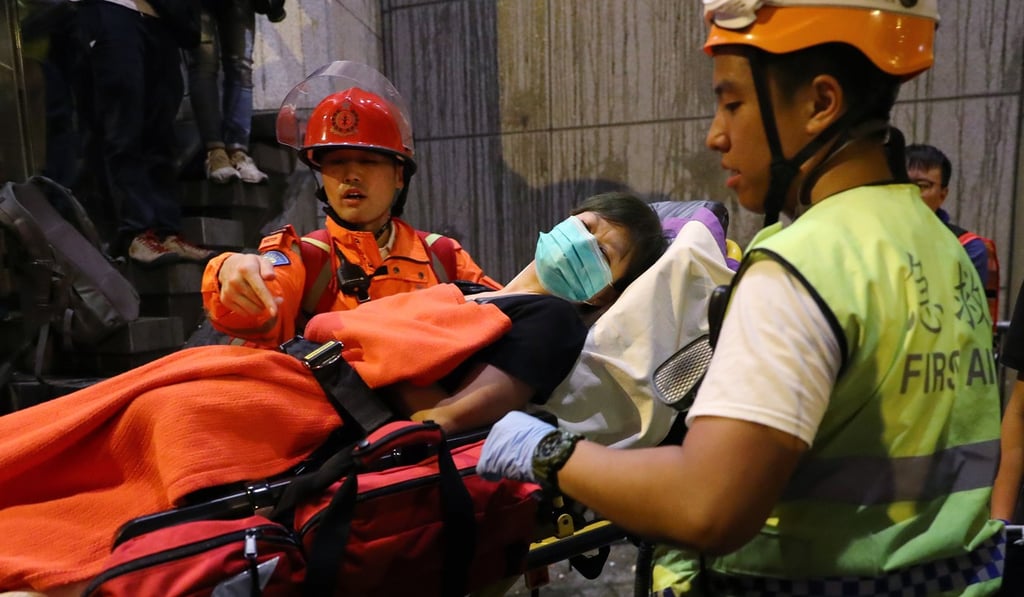 Emergency services staff move a woman from the Police Headquarters in Wan Chai while anti-extradition bill protesters surround the building. Photo: Edmond So