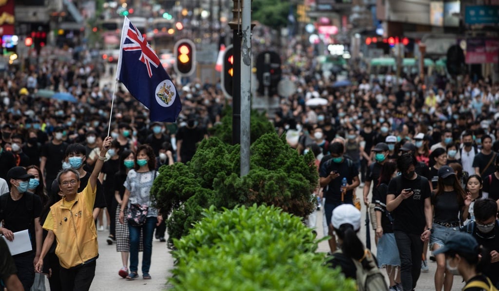 A man holds a British colonial flag during a rally along Nathan Road on August 3. Photo: AFP A man holds a British colonial flag during a rally along Nathan Road on August 3. Photo: AFP