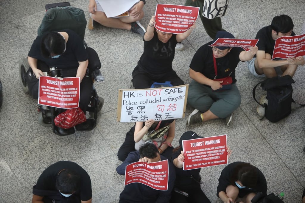 Extradition bill protesters hold up placards against police brutality during a sit-in at Hong Kong International Airport. Photo: Winson Wong