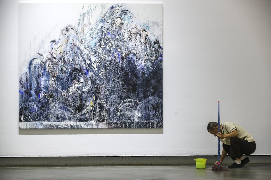 A Guangdong Museum of Art cleaner mops the floor next to one of British artist Maggi Hambling's Walls of Water series – large, violent paintings of crashing waves, a response to humanity’s destruction of Planet Earth. Photo: Edward Wong