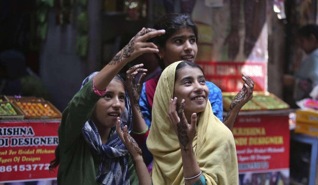Girls gesture after getting henna decorations on their hands on the eve of Eid al Adha, in Jammu, India. Photo: AP Photo