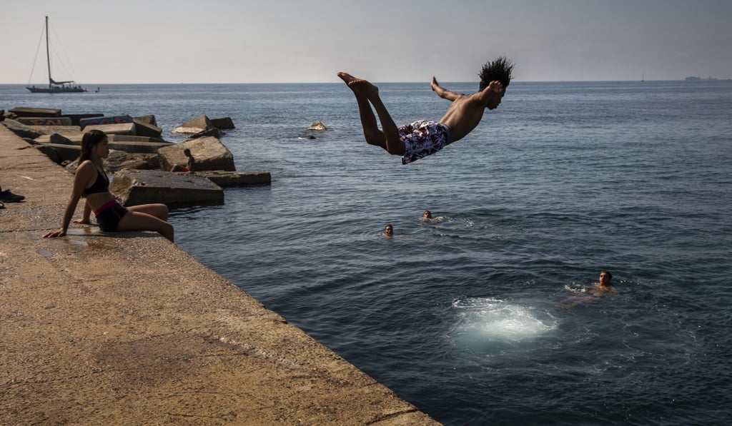 A boy jumps into the water at the beach in Barcelona in July. Photo: AP A boy jumps into the water at the beach in Barcelona in July. Photo: AP