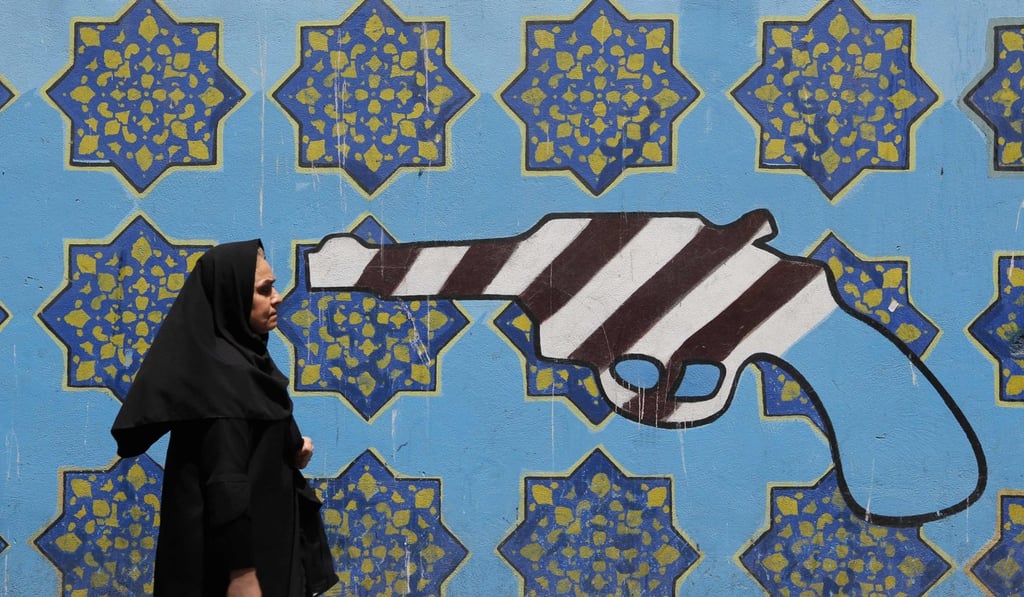 An Iranian woman passes a mural painting on the wall of the former US embassy in the Iranian capital Tehran. Photo: AFP