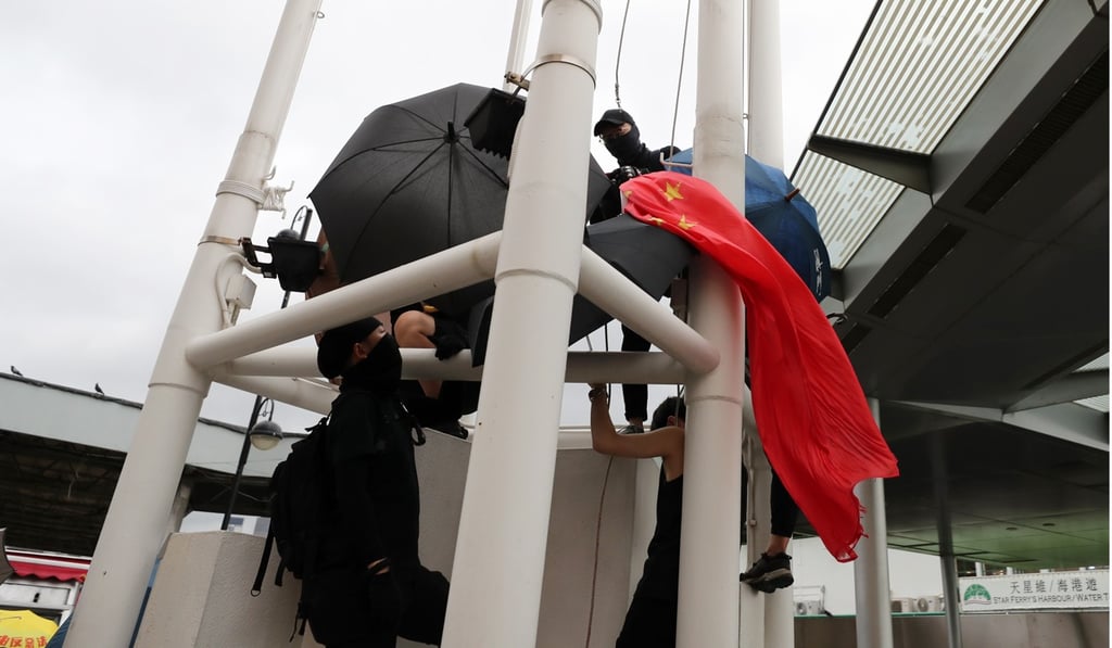 Protesters remove the national flag from a flagpole in Tsim Sha Tsui. Photo: Sam Tsang