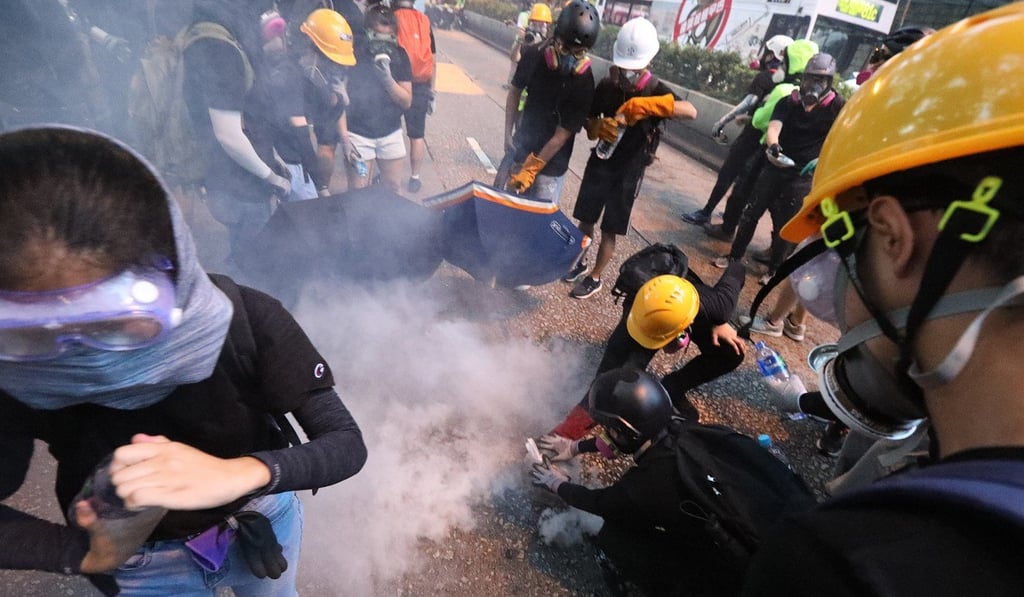 Anti-government protesters try to put out tear gas on Sunday in Tsim Sha Tsui, as demonstrations continue to be characterised by violence from various groups including police, protesters and their opponents. Photo: Felix Wong