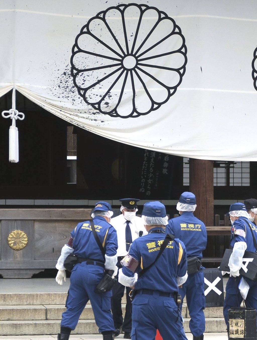 Police officers survey the vandalism in front of a worship hall at the Yasukuni Shrine in Tokyo. Photo: Kyodo