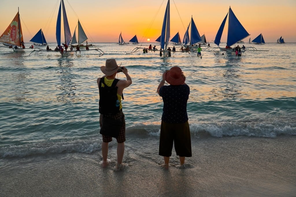 An elderly Asian couple enjoy the sunset at White Beach, Boracay Island, the Philippines. Photo: Alamy