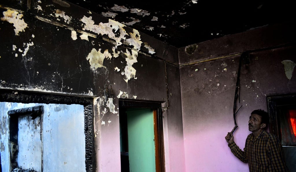 A man surveys Dar’s burned-down house. Photo: Sanna Irshad Mattoo