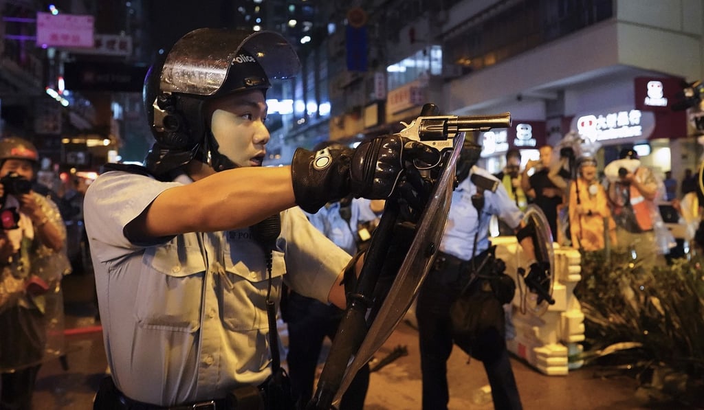 A policeman points a weapon during a protest on Sunday. Hong Kong police also rolled out a water cannon for the first time. Photo: AP A policeman points a weapon during a protest on Sunday. Hong Kong police also rolled out a water cannon for the first time. Photo: AP
