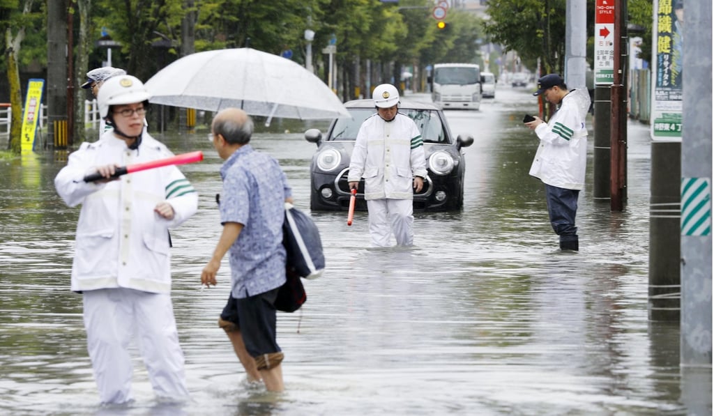 Pedestrians navigate flooded streets in Saga prefecture. Photo: Kyodo