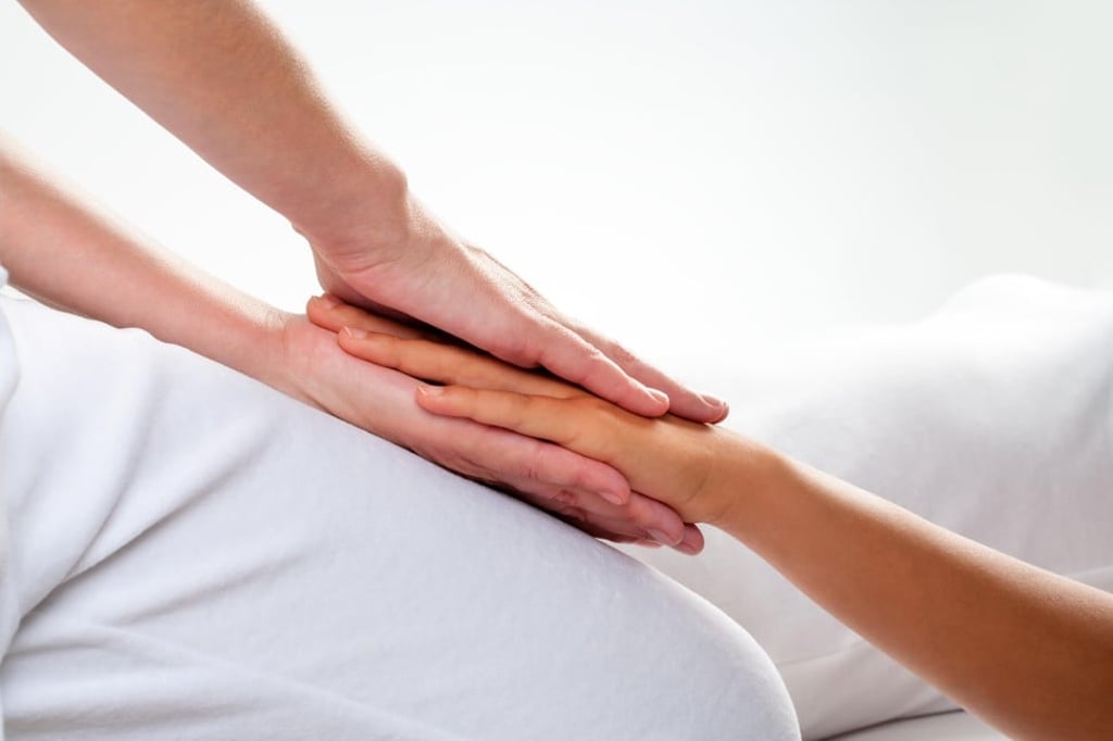 A chiropractor carries out reiki treatment on a girl’s hand. Photo: Alamy
