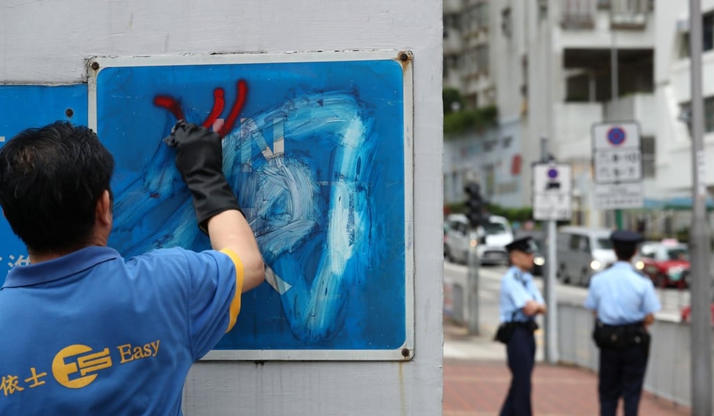 A cleaner scrubs graffiti off the outside the Tsuen Wan Police Station. Photo: Nora Tam