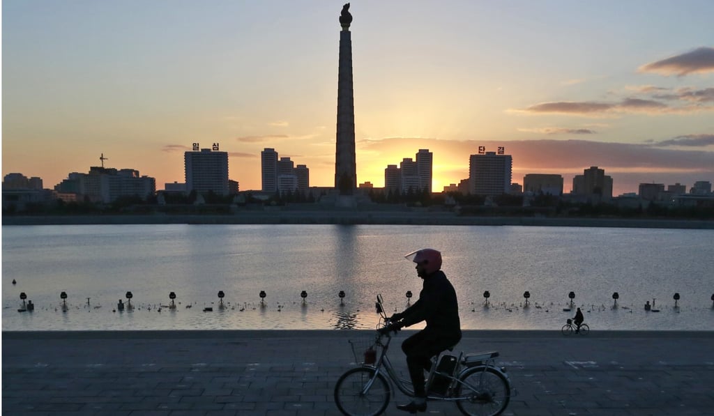 A man rides his electric bike in front of the Juche Tower in Pyongyang. Photo: AP