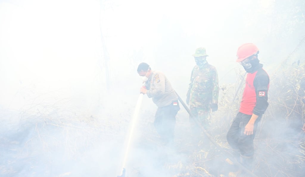 Firefighters spray water to help extinguish a fire in Kampar. Photo: AFP