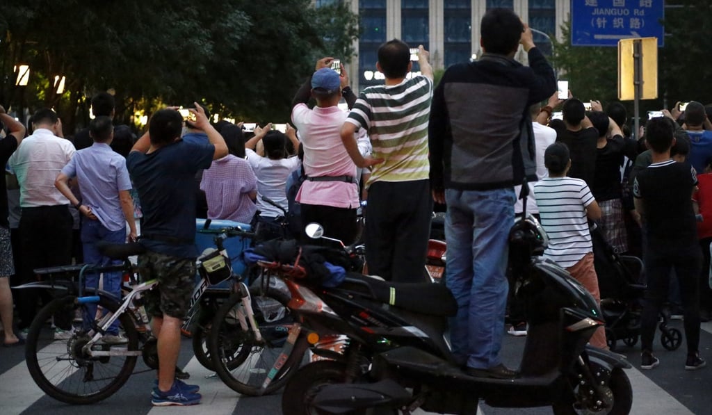 Crowds strain to get a look as military vehicles pass along a street in Beijing on Saturday. Photo: AP