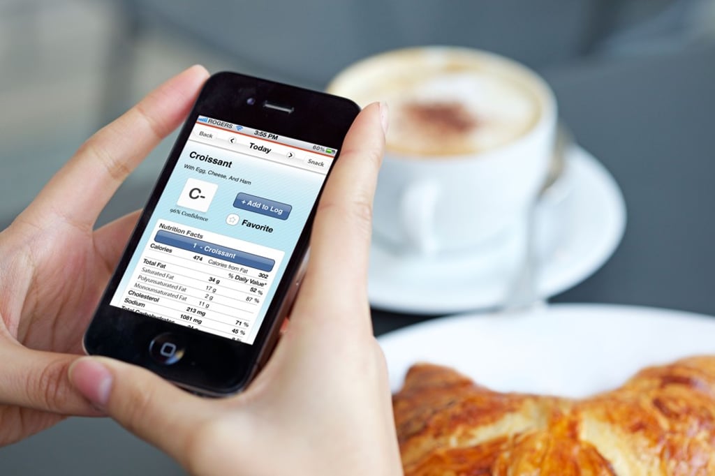 A health-conscious woman checks her food calorie intake using a calorie counter app on her iPhone. Photo: Alamy
