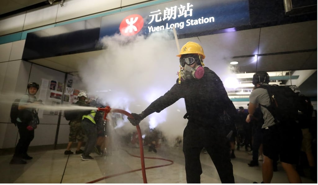 A protester uses a fire hose as Yuen Long MTR station is vandalised. Photo: Winson Wong