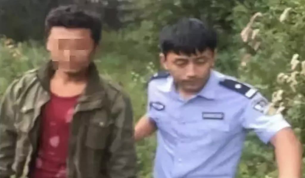 One of the men is escorted away by a police officer after the balloon landed safely. Photo: Weibo