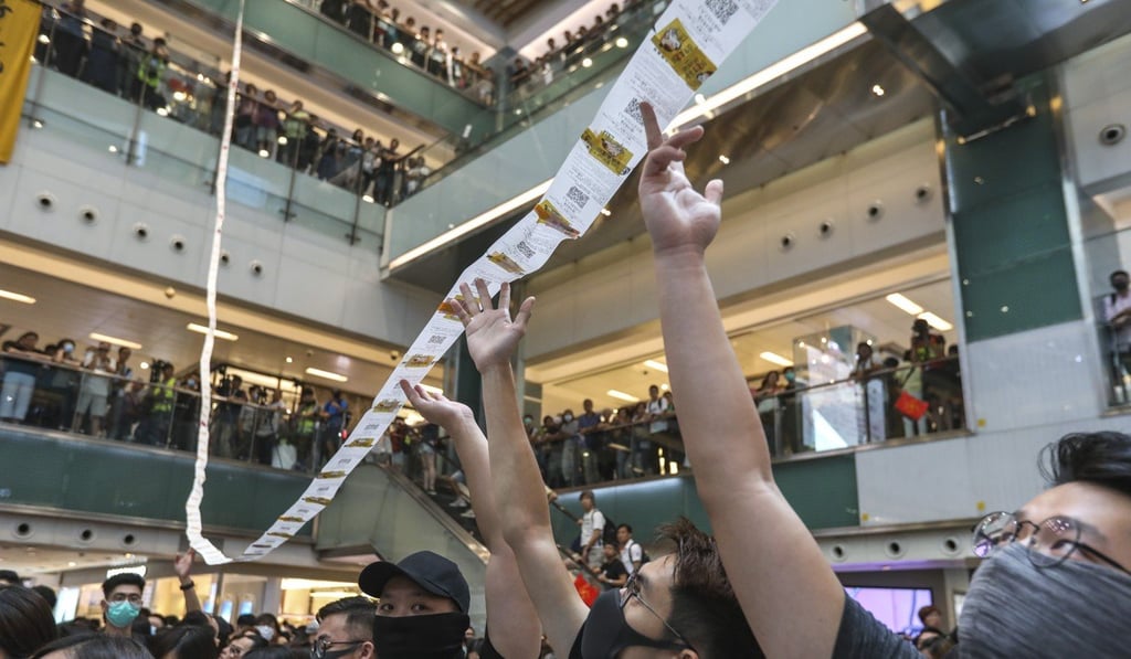 Protesters play with reservation slips printed out from a restaurant in New Town Plaza. Photo: Nora Tam