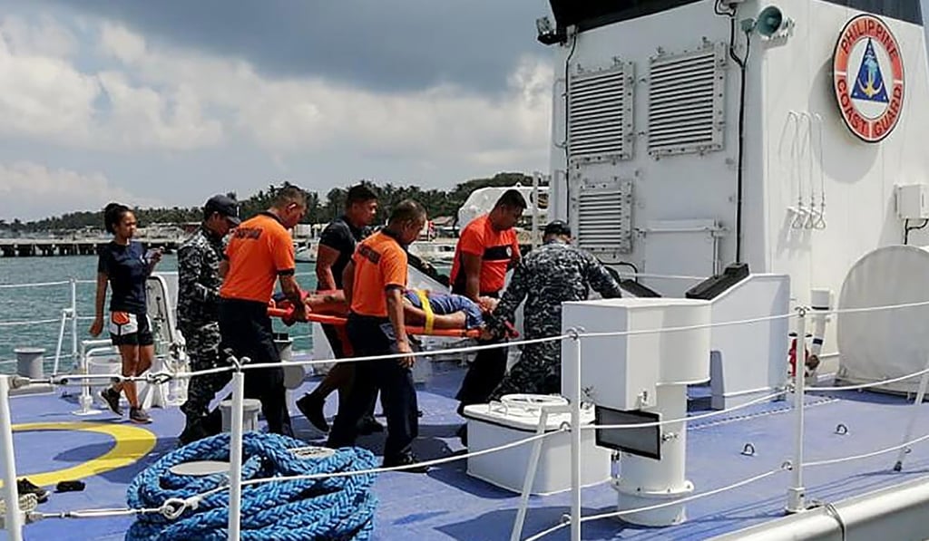 Coast guard personnel carry a survivor to an ambulance after being rescued from a capsized dragon boat. Photo: Philippine Coast Guard Via AP