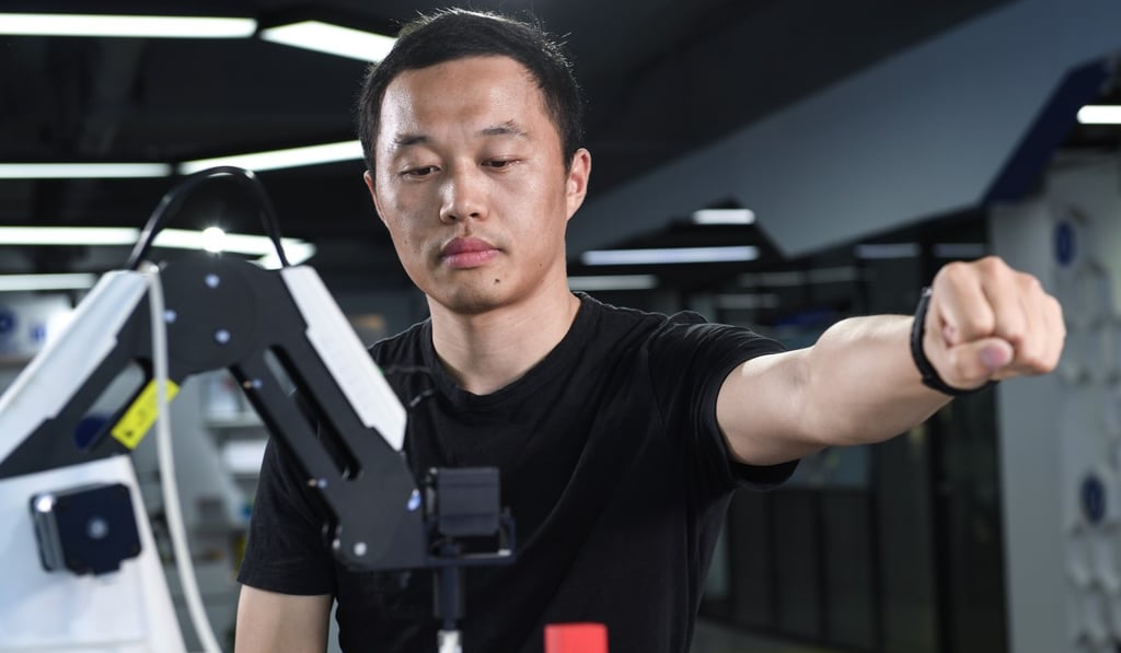 Liu Peichao, the founder and CEO of Yuejiang Technology, “teaching” his robotic arm with gestures. With a gesture sensor, the robot can learn what the hand is doing. Photo: Handout