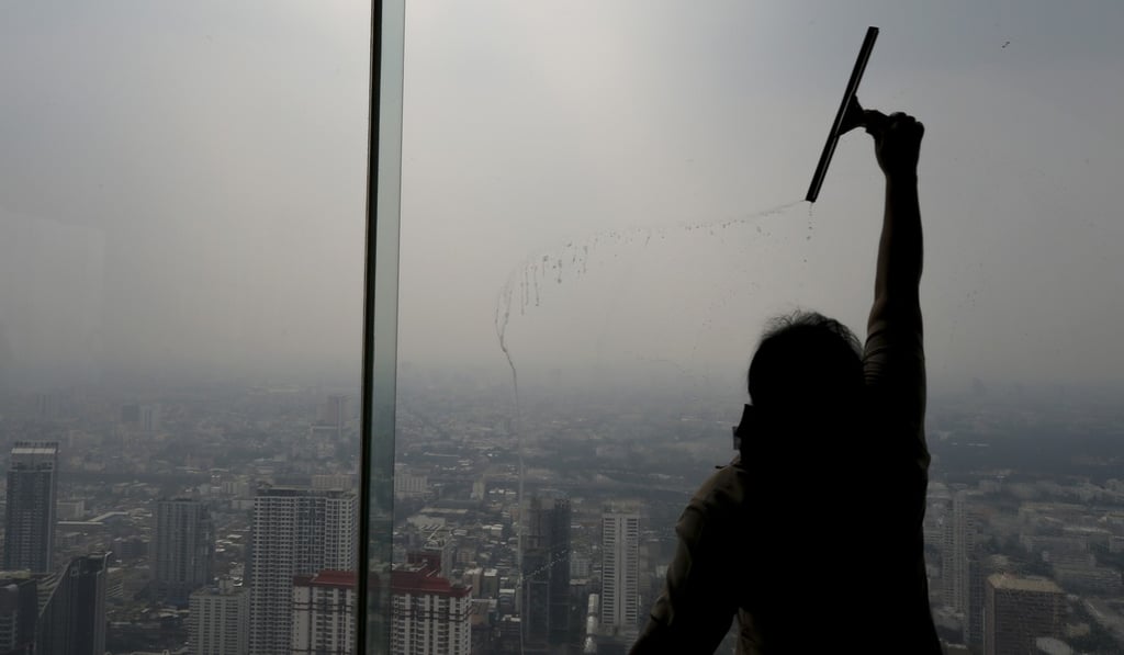 A worker cleans a window as smog and pollution shrouds buildings in Bangkok on Monday. Photo: EPA A worker cleans a window as smog and pollution shrouds buildings in Bangkok on Monday. Photo: EPA