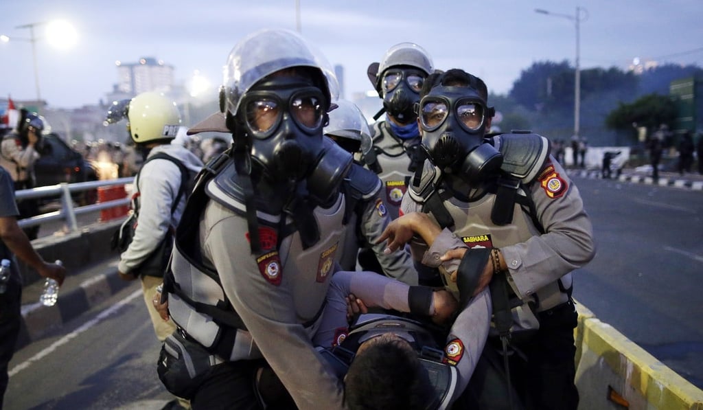 Indonesian riot police officers carry an injured colleague during a clash with students outside parliament in Jakarta. Photo: EPA Indonesian riot police officers carry an injured colleague during a clash with students outside parliament in Jakarta. Photo: EPA