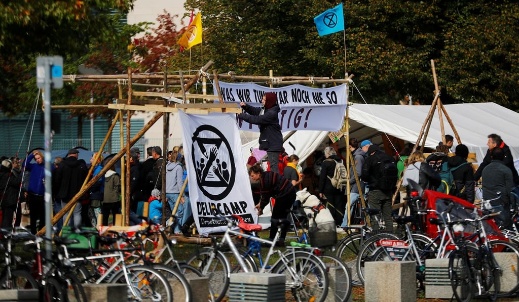 People set up a banner with the Extinction Rebellion (XR) symbol at a makeshift camp of climate activists next to the Reichstag building in Berlin, Germany. Photo: Reuters People set up a banner with the Extinction Rebellion (XR) symbol at a makeshift camp of climate activists next to the Reichstag building in Berlin, Germany. Photo: Reuters