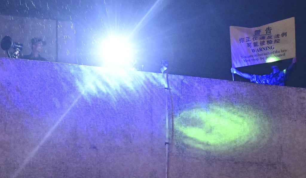 A PLA soldier raises a yellow banner with a warning for protesters in Kowloon Tong. Photo: Handout