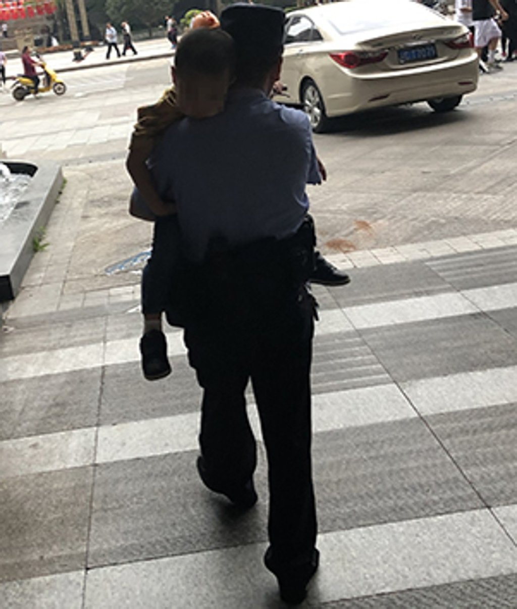 An officer from Chongqing police carries the sleepy four-year-old boy to Dazhu district station and an eventual reunion with his father. Photo: Weibo