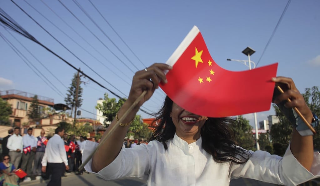 A woman waves a Chinese flag to welcome Xi Jinping to Nepal. Photo: AP