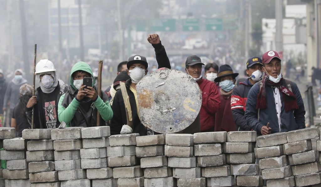 Anti-government demonstrators take cover behind a barricade in Quito. Photo: AP