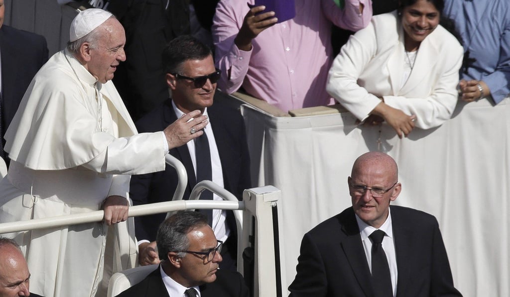 Domenico Giani, right, flanks Pope Francis' Popemobile in St Peter's Square at the Vatican. Photo: AP Domenico Giani, right, flanks Pope Francis' Popemobile in St Peter's Square at the Vatican. Photo: AP