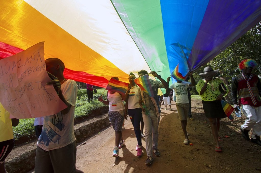 People walk under a giant rainbow flag as they take part in the gay pride parade in Entebbe, Uganda in 2015. Photo: AFP