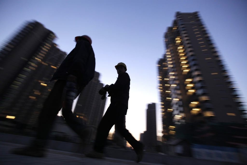 Workers walk past apartment blocks under construction in Beijing. Photo: Reuters