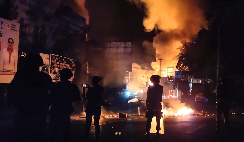 Indonesian security forces watch as a building burns after hundreds of demonstrators marched near Papua’s biggest city Jayapura, where they set fire to a regional assembly building and hurled rocks at shops and hotels. Photo: AFP