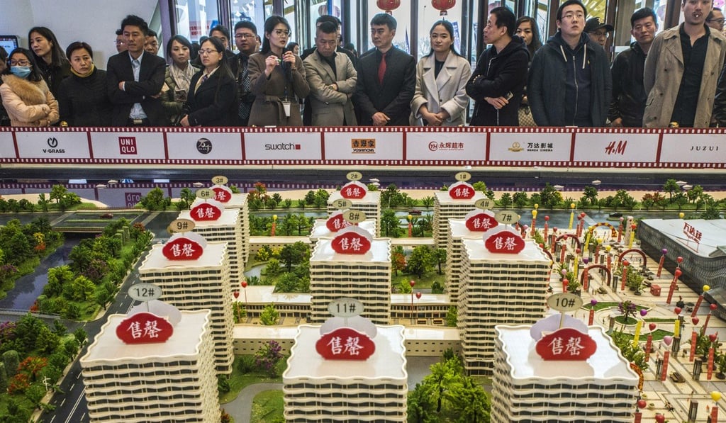 Prospective customers look at a model of the Dalian Wanda Group’s property project in Qingdao, China. Photo: Bloomberg
