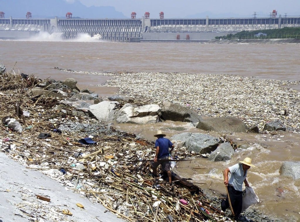 Chinese workers pick up waste swept in by flood waters near the Three Gorges Dam at the Yangtze River, in Yichang, in China's Hubei province. Photo AP